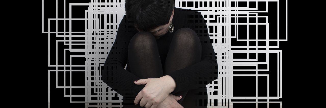 What Does an Autistic Shutdown Feel Like? Sad woman sitting on floor with geometric art behind her.