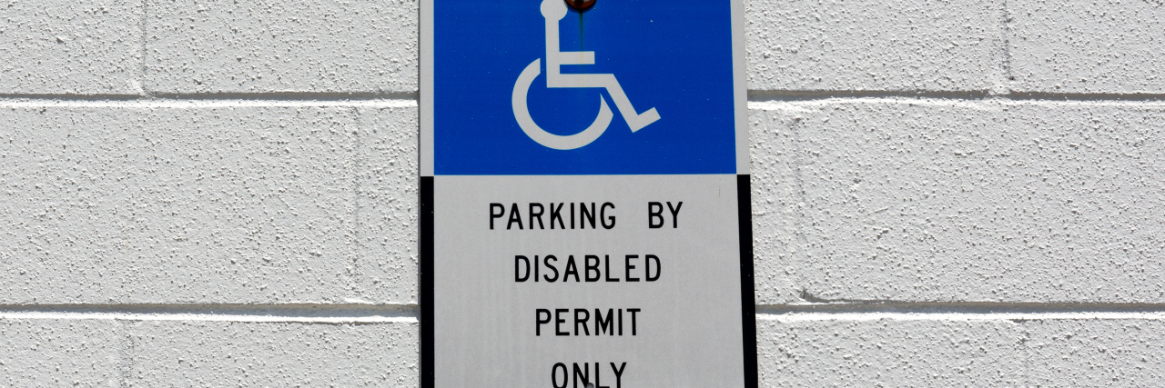 Blue and white disabled parking sign on wall..
