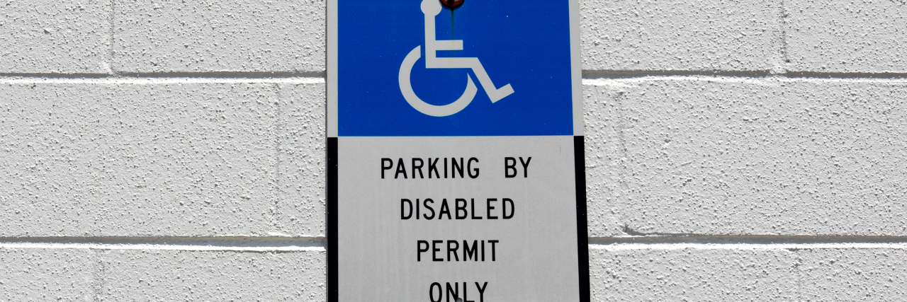 Deciding to Get a Disability Parking Placard Due to a Chronic Illness Blue and white disabled parking sign on wall..
