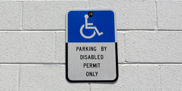 Blue and white disabled parking sign on wall..