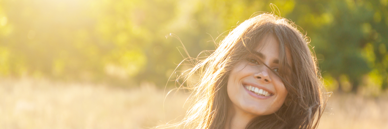 Why Happy Autistic People Often Can't Get a Diagnosis Happy woman in a field.