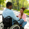 Black couple. The husband uses a wheelchair and his wife appears to be able-bodied.