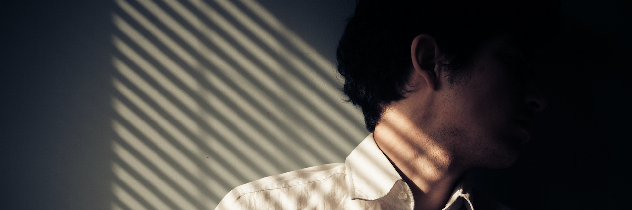 The Effects of Heat and UV Radiation on Those With Chronic Illness Young man next to a window with shadows being cast from the blinds