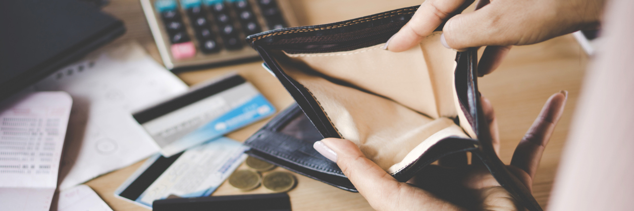 What It Feels Like After Spending Too Much Money While Manic an open, empty wallet with credit cards and a calculator laying on the table