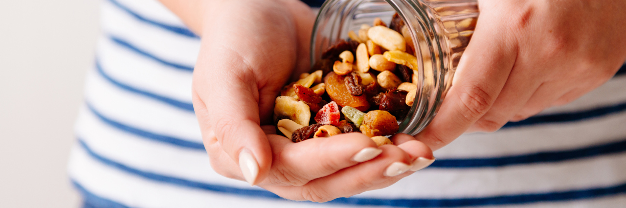 Eating Hacks for When Depression and Anxiety Make It Hard to Eat photo of a person's hands pouring dried fruit and nuts from a glass jar