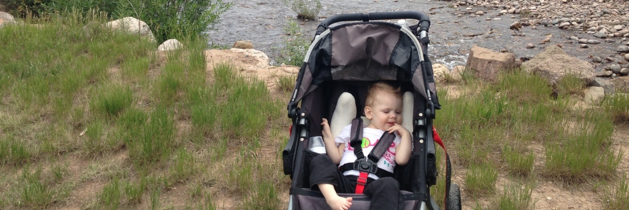 Photo of baby June in stroller sitting in front of a beautiful river and mountain