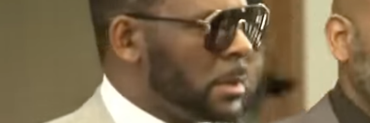 What Trauma Survivors Need to Know About the Upcoming R. Kelly Trial screenshot of R. Kelly wearing sunglasses during period of trial for sexual abuse allegations