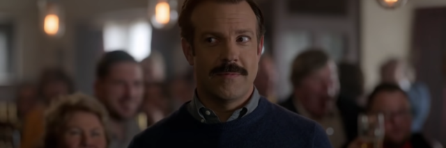 screenshot of Ted Lasso main character smiling to someone off-camera