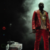 Kanye West standing on stage in a red suit