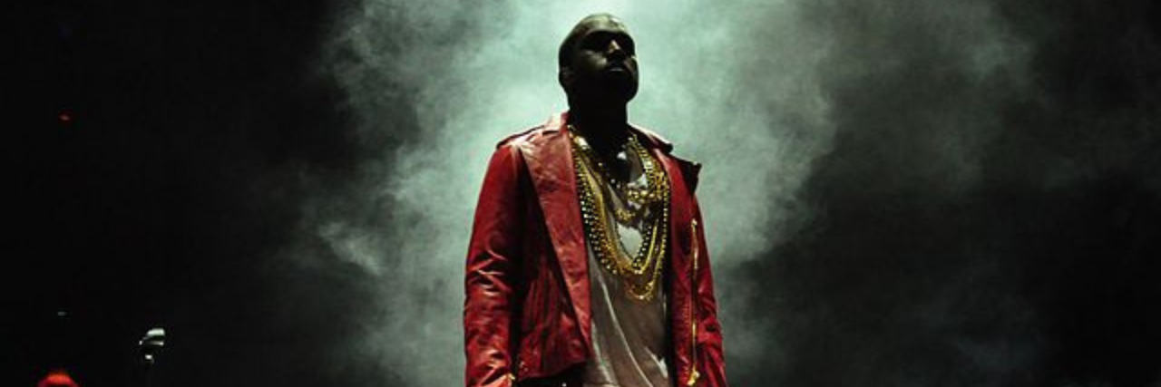 Kanye West standing on stage in a red suit