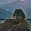 photo of a sad looking woman looking into the camera with a mountain behind her