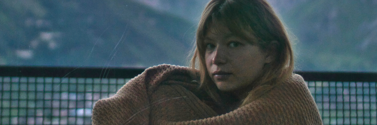 When You Struggle to Accept Your Trauma is Real and 'Valid' photo of a sad looking woman looking into the camera with a mountain behind her