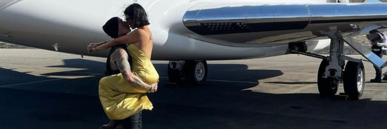 photo of Travis Barker from Blink-182 and Kourtney Kardashian in front of a private jet after his first flight since his 2008 plane crash