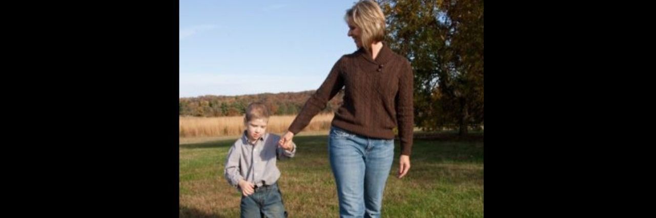 a mother and young son walking in a field