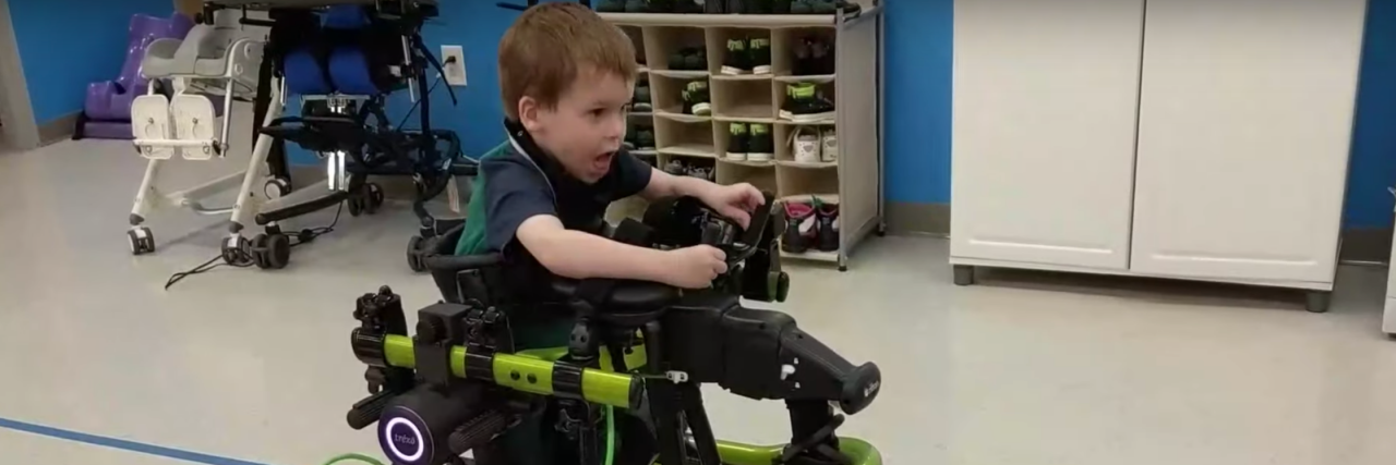 A young child using a green version of Trexo Robotic's mobility aids.
