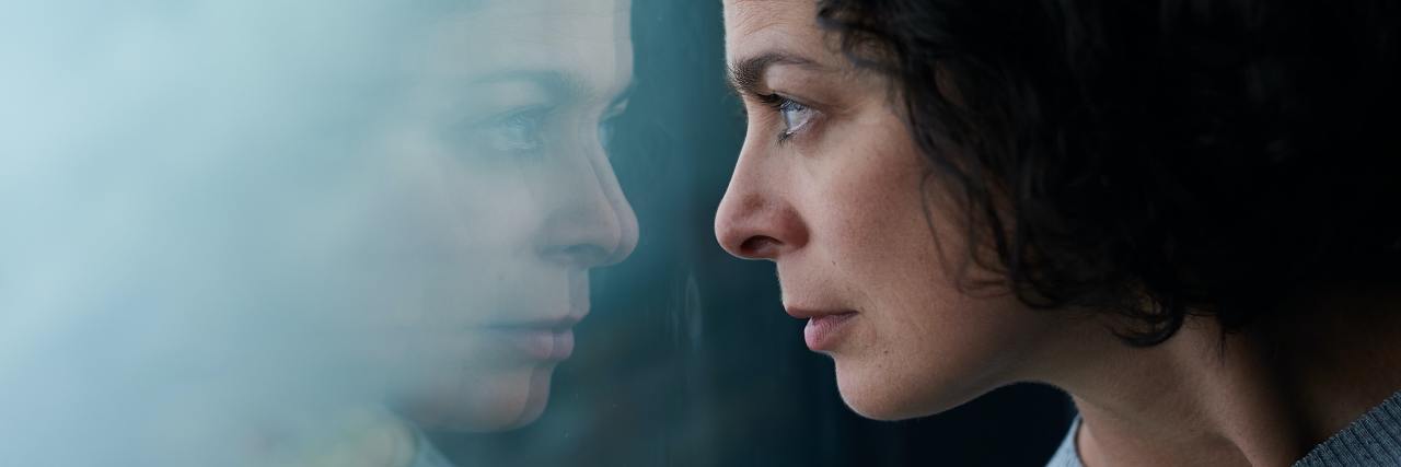 Seeking Help for the Physical Consequences of My Eating Disorder photo of a woman looking into her reflection in a glass window
