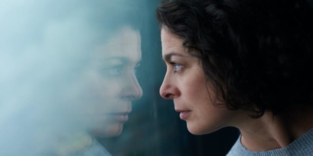 How I Am Navigating the Physical Consequences of My Eating Disorder photo of a woman looking into her reflection in a glass window