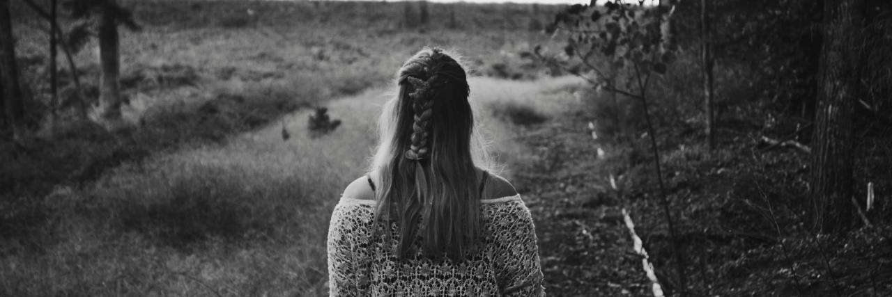 What You Should Know About Complex PTSD (and How to Cope With It) Black and white photo of the back of a woman in a dress walking on a trail