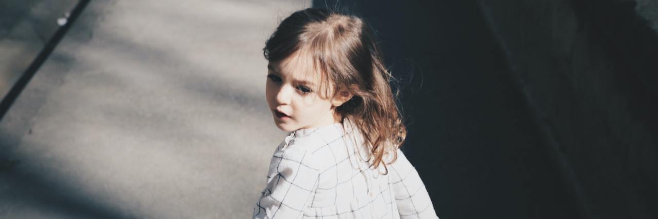How to Heal When Childhood Trauma Kept You From Expressing Emotions Little girl with brown hair looking behind while running down the sidewalk