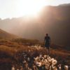 photo of a man standing among mountains with sun setting