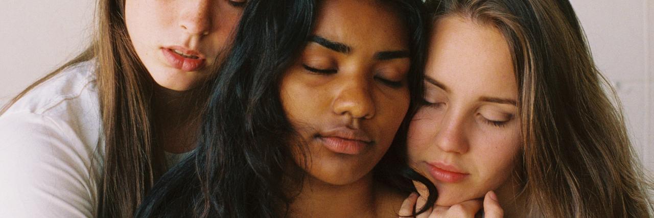 What to Know About Changing Friendships in Mental Health Recovery photo of three women sitting close to each other, embracing with eyes closed