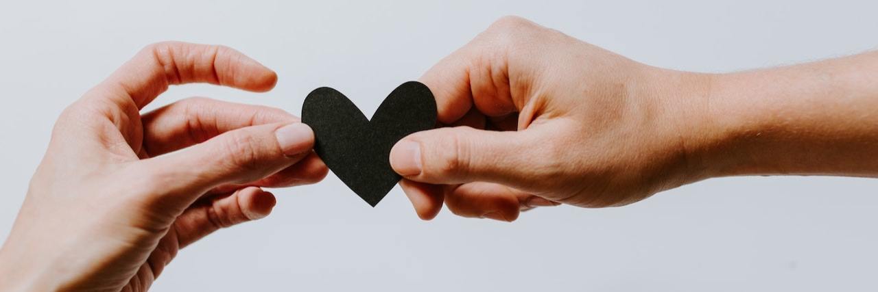 Caring for Someone Else and Yourself With Chronic Illness Photo of two hands holding a small heart