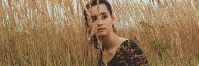 photo of a woman sitting in a field of long grass
