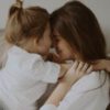 photo of a mother and daughter playing and hugging on a bed