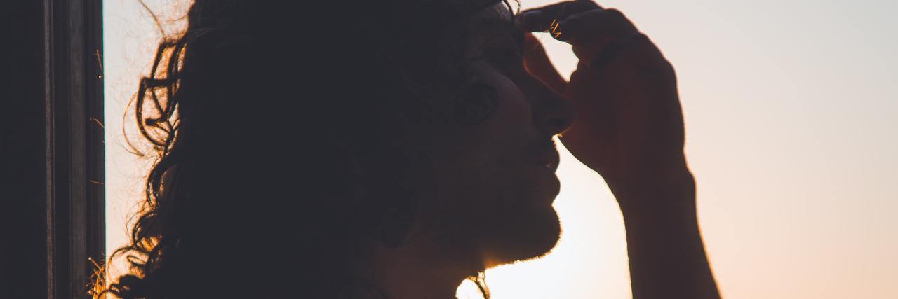 Read This if You’re Struggling With Receiving Multiple New Diagnoses photo of a woman at sunset looking overwhelmed silhouetted against light