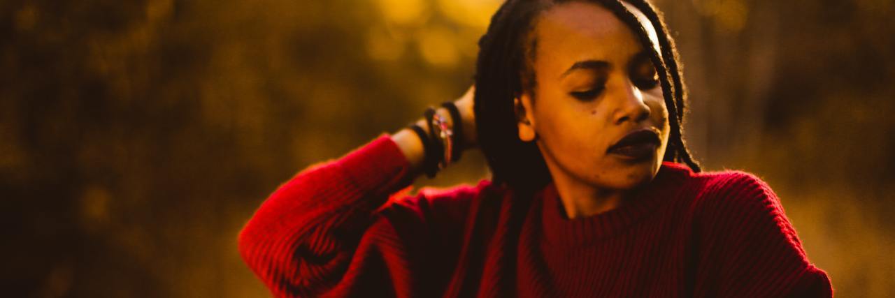 Why Calling Me a ‘Strong Black Woman’ Is Compromising My Mental Health photo of a woman at sunset with her eyes clsoed, hand raised to the back of her head