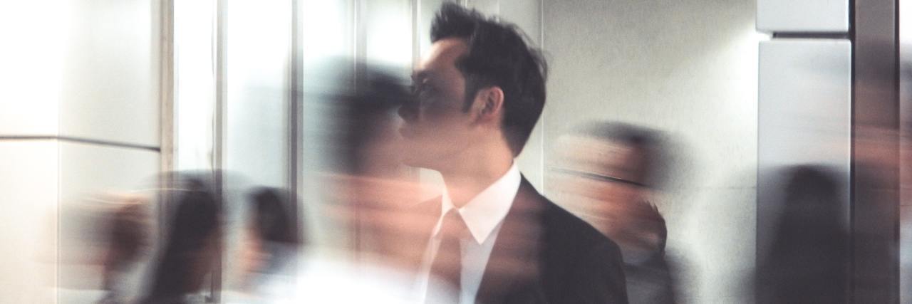 My Experience With Both Bipolar Mania and ADHD photo of a man in a busy crowd, people blurred around him