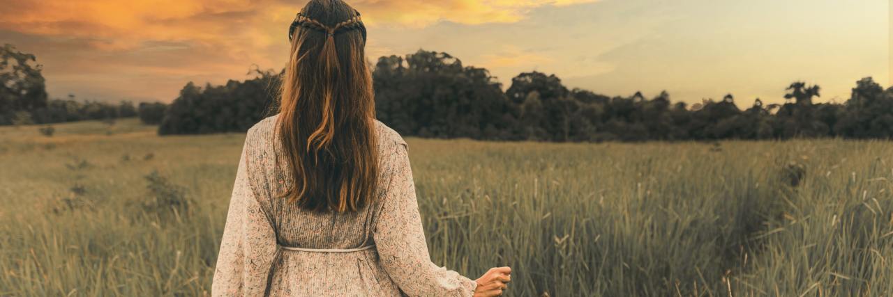 Stop Thinking All Active and Passive Suicidal Ideation Are the Same photo of a woman in a field at sunset, wearing a white dress, facing away from the camera