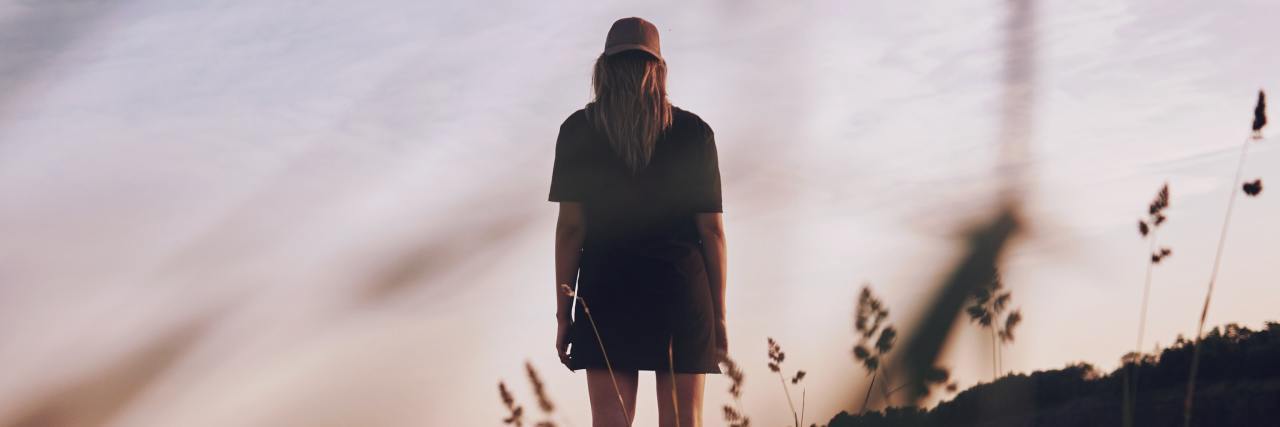 A Letter to My Therapist About the Hurt He Caused and Help He Gave Back of a woman in a black dress standing in a field of grass