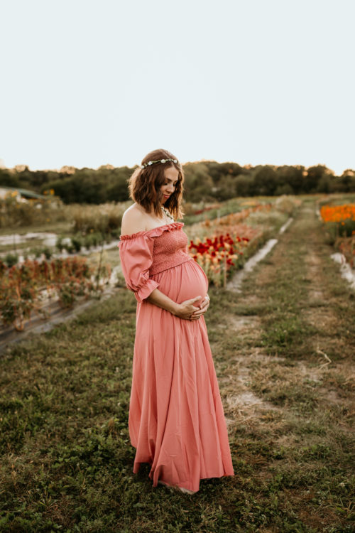 Photo of contributor wearing a long, coral dress and holding her pregnant belly