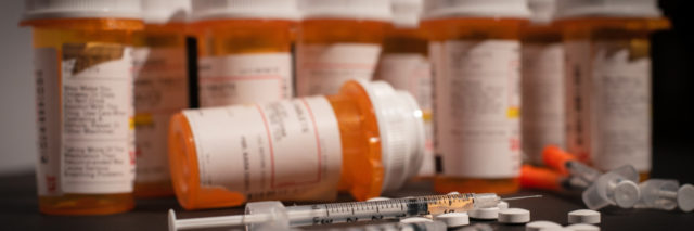 Syringe, pills, and prescription bottles.