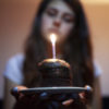 a woman staring at a candle while holding a birthday cake