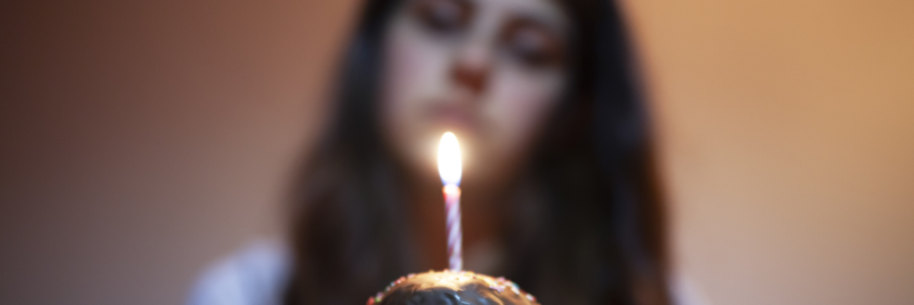 a woman staring at a candle while holding a birthday cake