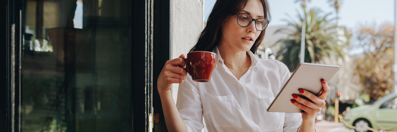How The Mighty Gave Me the Courage to Share My Health Story Woman reading at a coffee shop.