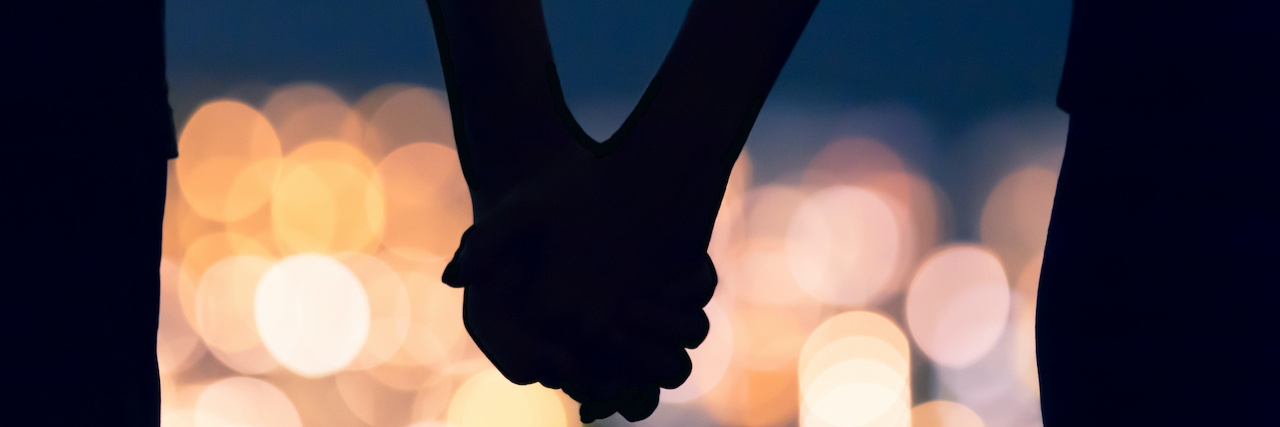 Experiencing a Molar Pregnancy When You Have Multiple Sclerosis Silhouette of cuple holding hands against blurred city night lights.