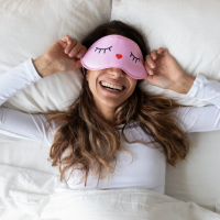 Woman waking up wearing an eye mask.