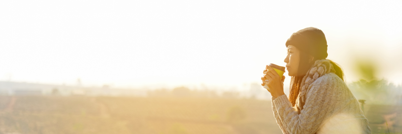 What to Remember When Your Health Changes Quickly Woman wearing sweater, sitting and drinking outdoors at sunrise.