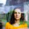 woman looks thoughtfully and sadly through the window