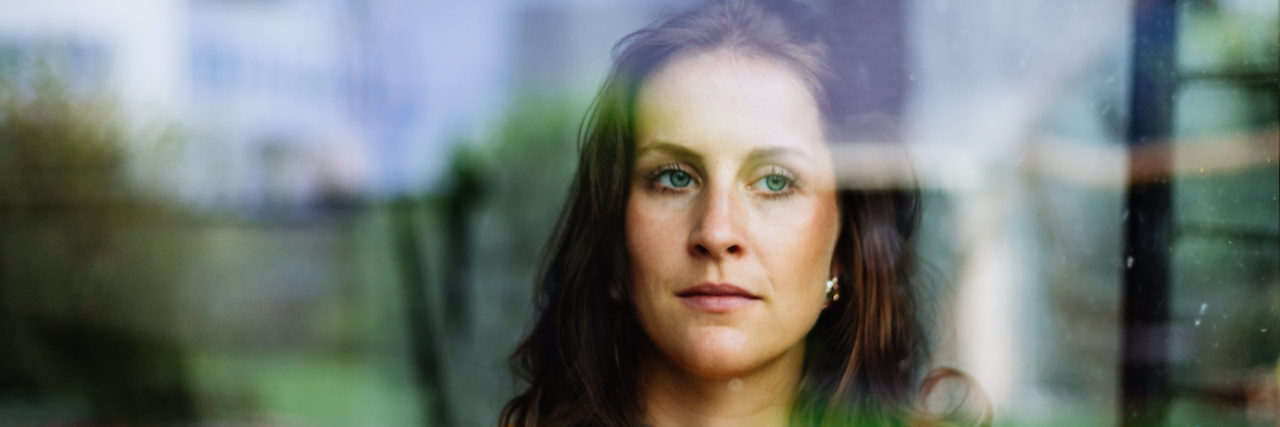 Dealing With Grief From What Endometriosis Stole From Me woman looks thoughtfully and sadly through the window