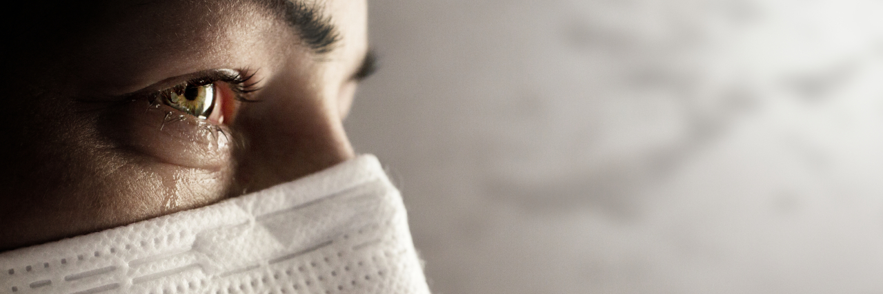 Lessons Learned From Grief Since My Husband's COVID Death a woman wearing a face mask with tears in her eyes