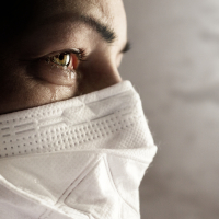 a woman wearing a face mask with tears in her eyes