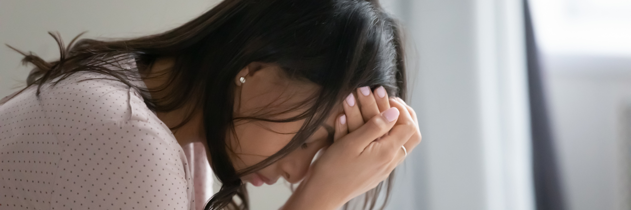 Why We Should Say 'Migraine' and Not 'Migraines' Woman with migraine holding her head.