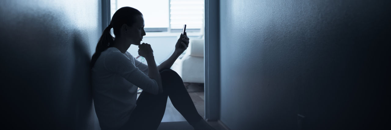 woman sitting in dark holding her cell phone