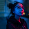 Night portrait of woman with glasses looking at neon lights