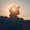 Woman wearing a hat outdoors at sunset.