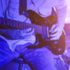 Closeup of person playing electric guitar on stage